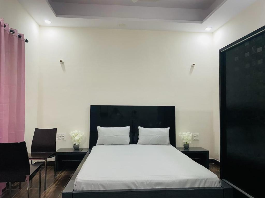 a bedroom with a white bed with two chairs at The Nest spacious and homely flat in Haldwani in Haldwāni