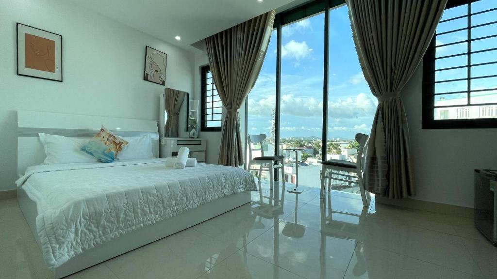 ein weißes Schlafzimmer mit Bett und Balkon in der Unterkunft Ruby Star Hotel Apartment in Vũng Tàu