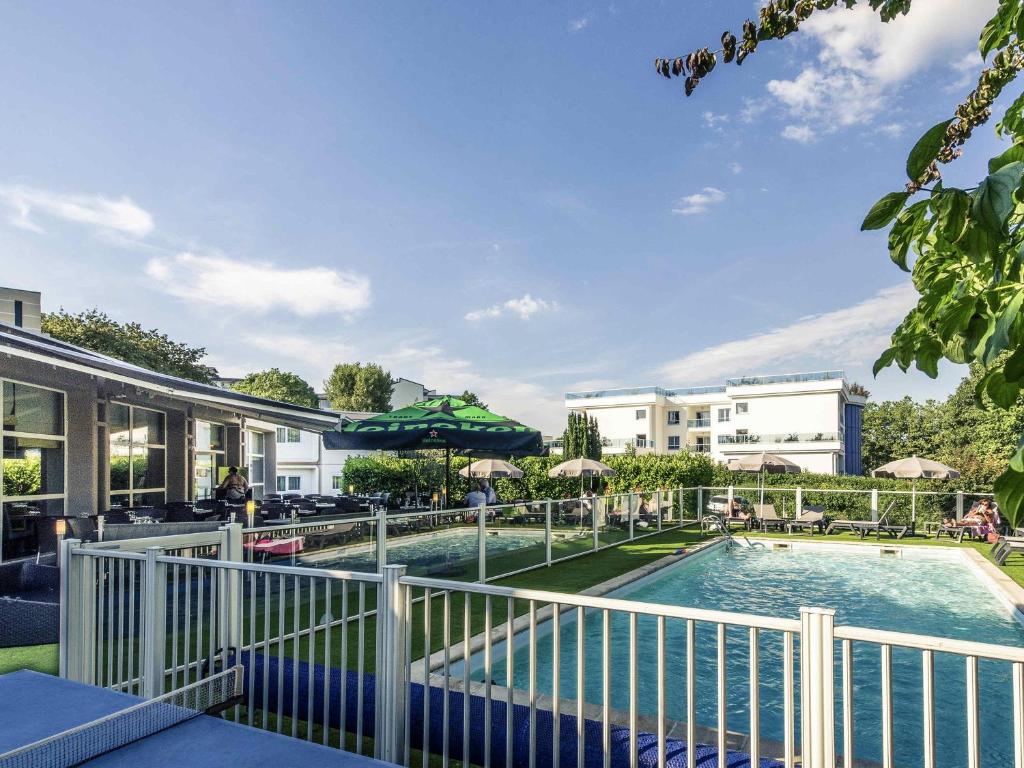 a pool at a resort with chairs and umbrellas at Mercure Annecy Sud in Annecy