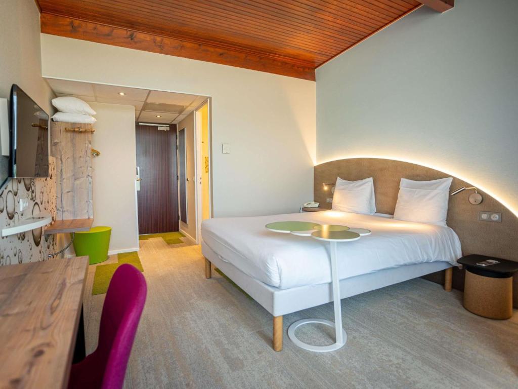 a bedroom with a bed and a table in it at Ibis Styles Colmar Nord in Colmar