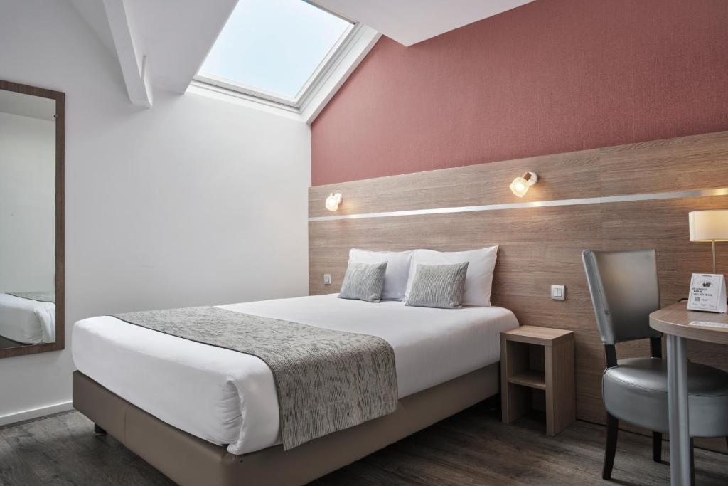 une chambre d'hôtel avec un lit, un bureau et une fenêtre dans l'établissement The Originals City, Le Beaujoire, Nantes - En face du Parc des Expositions et face au Stade Beaujoire, à Nantes