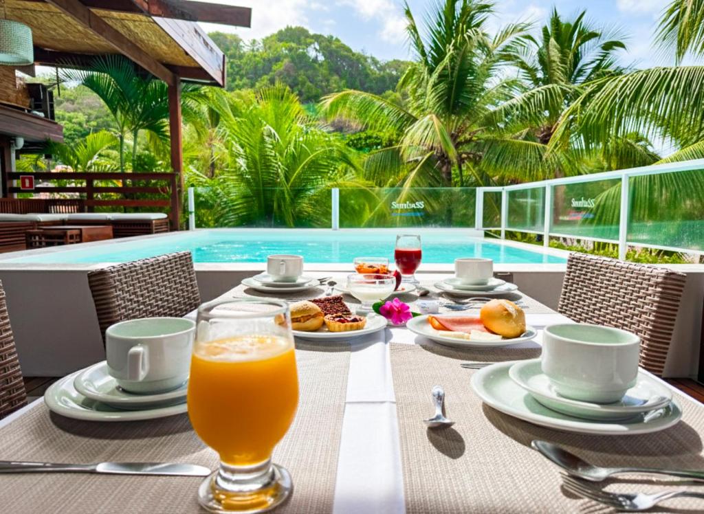 - une table avec de la nourriture et un verre de jus d'orange dans l'établissement Pousada Sambass, à Morro de São Paulo