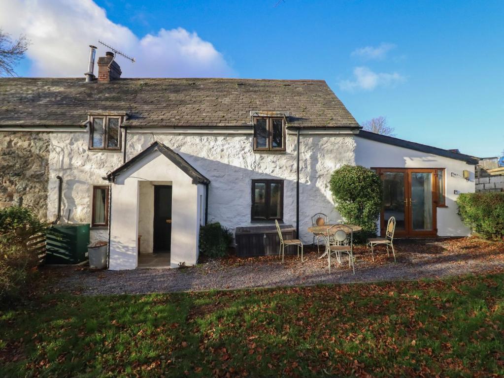 une vieille maison avec une table et des chaises devant dans l'établissement 1 Fron Uchaf, à Frongoch
