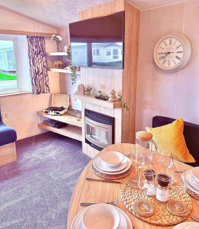 a living room with a table and a fireplace at The Eden - Sleeps 8 Pet Friendly Free Wi-Fi With Patio & Hub Passes Camber Sands Cosy Spacious Modern 8 Berth Caravan in Camber