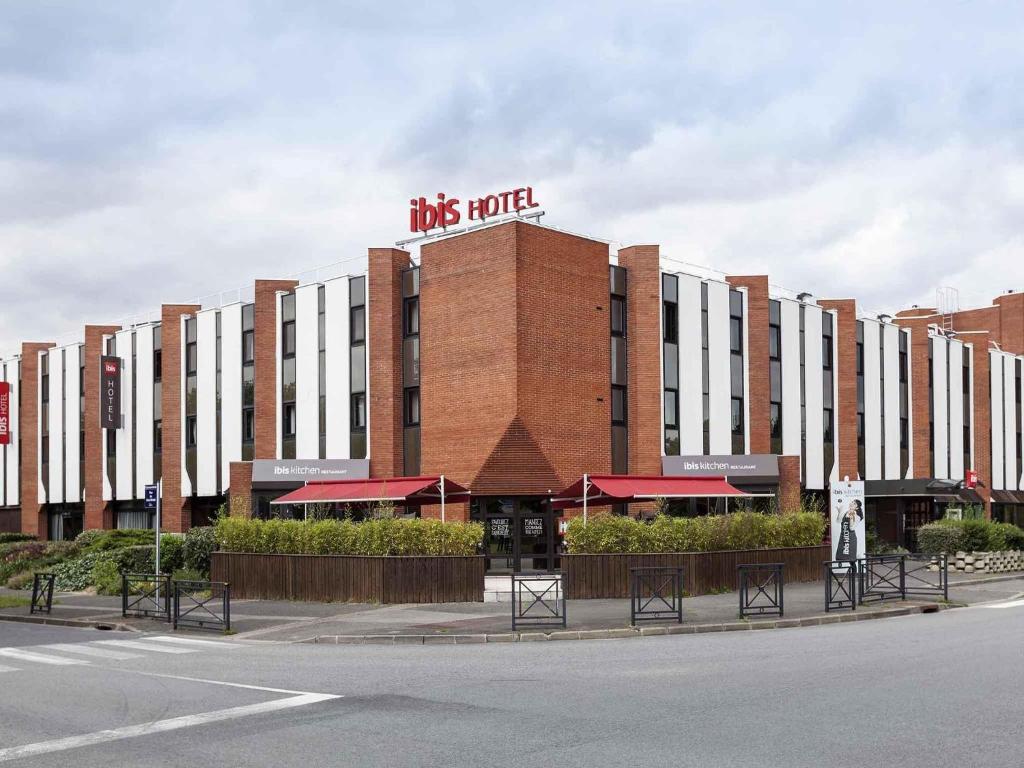 a brick building with a sign on top of it at Ibis Évry-Courcouronnes in Evry-Courcouronnes