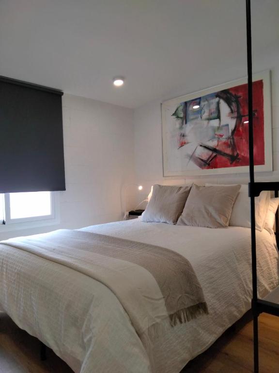 a bedroom with a large white bed with a window at Visitar La Campana in La Campana