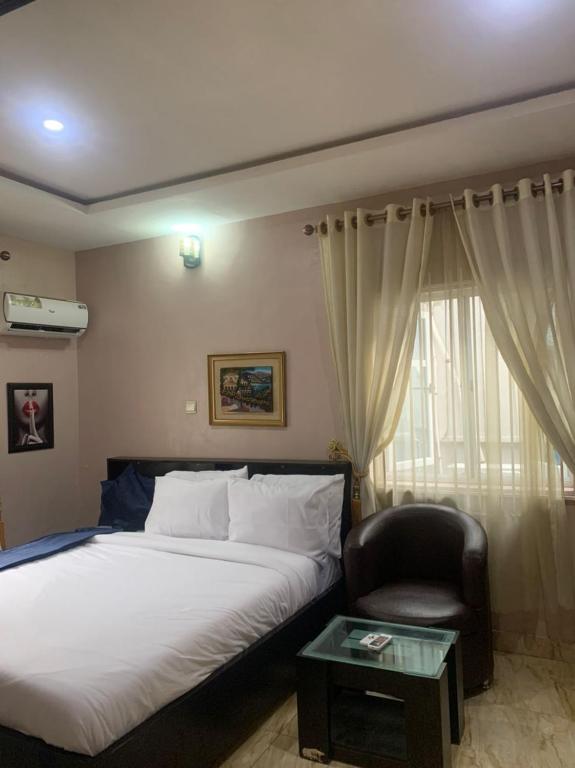 Un dormitorio con una cama, una silla y una ventana en MoAde, en Ikeja