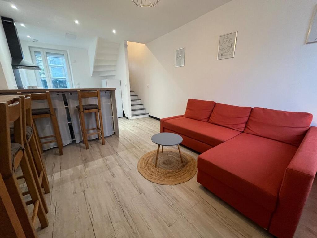 a living room with a red couch and a table at Maison Arques-la-Bataille à 5min de Dieppe in Arques-la-Bataille