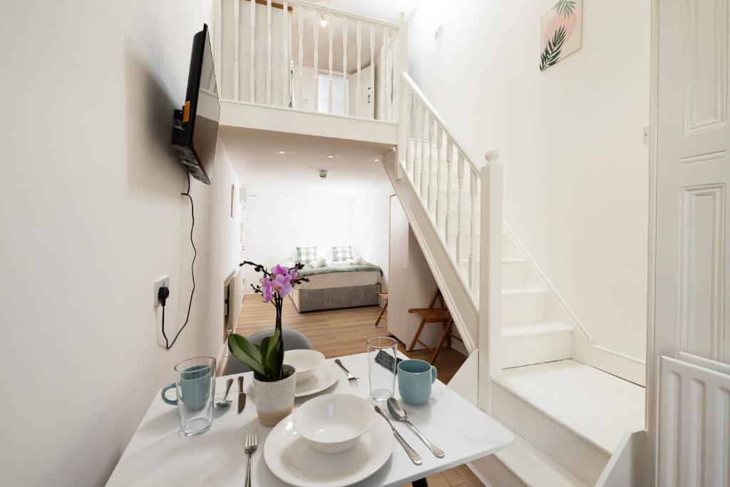 a white room with a table and a staircase at Charmstay Swiss Cottage in London