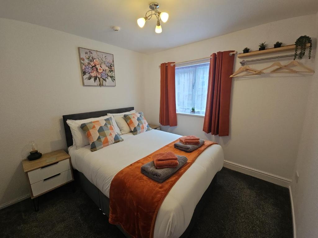 a bedroom with a bed with red curtains and a window at Data House Apartments ONE in Atherstone
