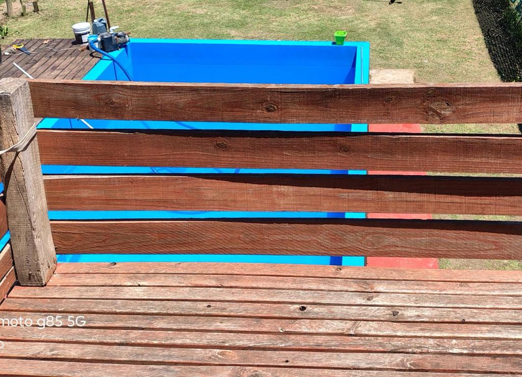 a wooden bench with blue paint on a wooden deck at Cabaña Anisacate in Villa Anizacate