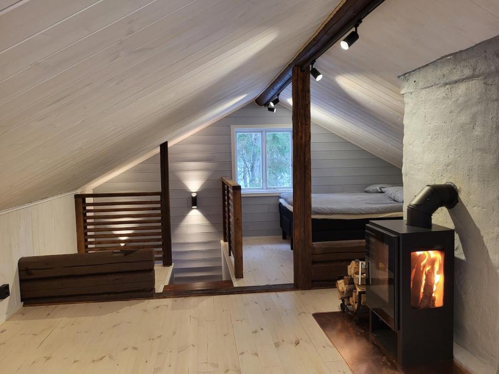 a attic room with a bed and a fireplace at Villa Hattara - a cottage on the shore of a rapid in Nukari
