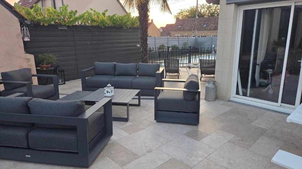 eine Terrasse mit Sofas, einem Tisch und einem Tisch in der Unterkunft Villa pour 24h auto le mans in Teloché