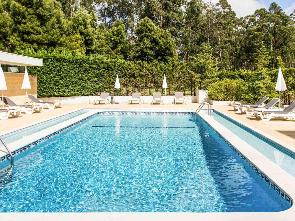 Hotel ibis Porto Sul Europarque في سانتا ماريا دا فييرا: مسبح مع كراسي جلوس الكراسي ومسبح