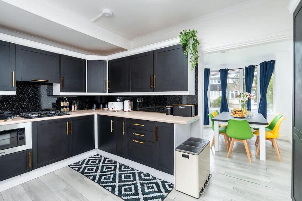 a kitchen with black cabinets and a table and chairs at Spacious 4 Bedroom House with 8 Beds and Private Driveway Parking in Heeley