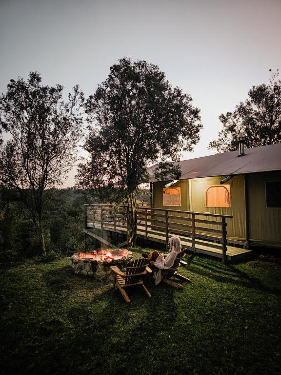 a person sitting on a picnic table next to a house at AfriCamps at Ingwe in Plettenberg Bay