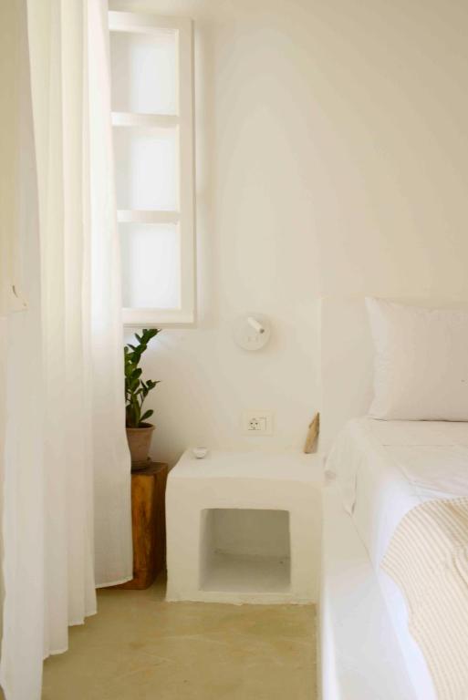 a white bedroom with a bed and a table at The endless blue hide out in Ios Chora