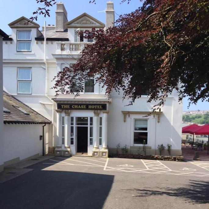 a white building with a sign that reads the guest house at Chase Hotel in Whitehaven