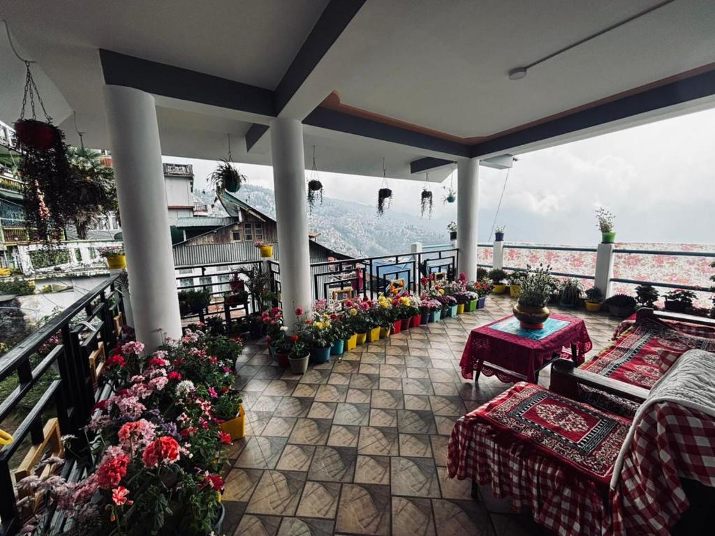 a balcony with tables and flowers and a mountain at V V Homestay in Darjeeling