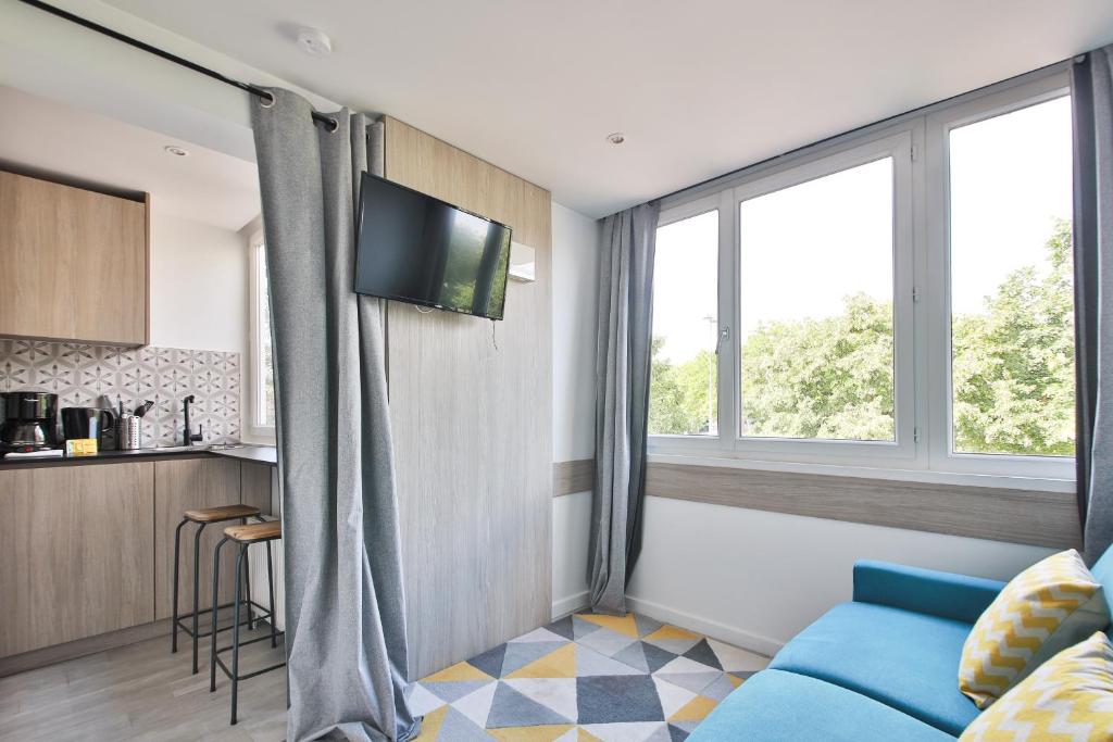 ein Wohnzimmer mit einem blauen Sofa und Fenstern in der Unterkunft Louis Vicat 4 - CI - Apartment for 2 Parc Expo Porte de Versailles in Paris