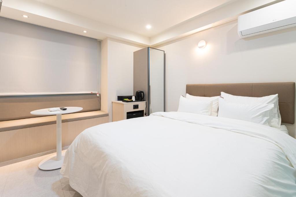 a bedroom with a large white bed and a table at 스테이쉼 발산 in Seoul