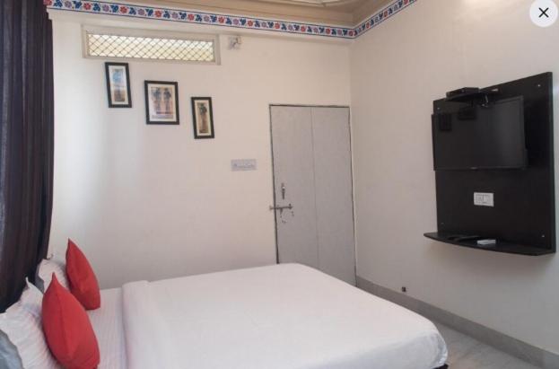 Un dormitorio con una cama blanca y un televisor de pantalla plana. en HOTEL ARAWALI UDAIPUR CITY BEST couples friendly stay, en Udaipur