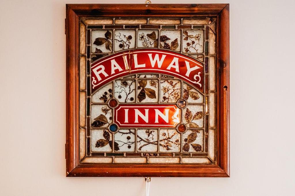 een bord in een houten frame op een muur bij The Railway in Skipton