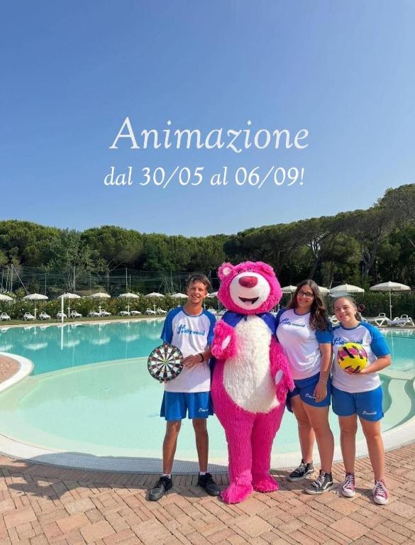 a group of children standing next to a pool with a mascot at Camping I Melograni in Marina di Bibbona
