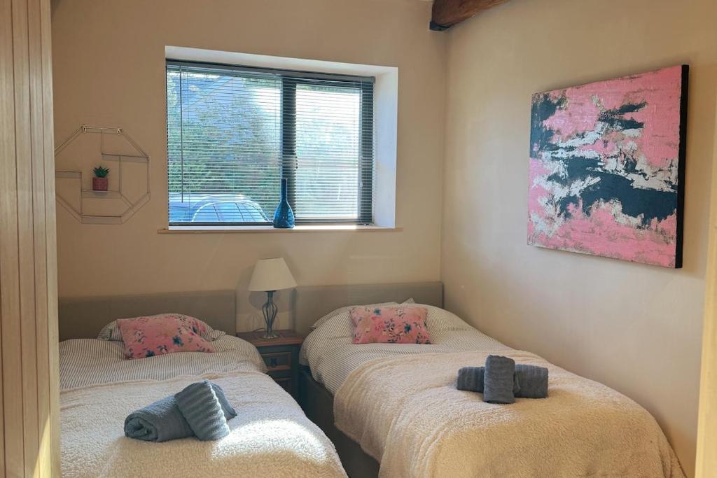 zwei Einzelbetten in einem Zimmer mit Fenster in der Unterkunft Trendy Barn Conversion Families & Groups Sleeps 8 in Midsomer Norton