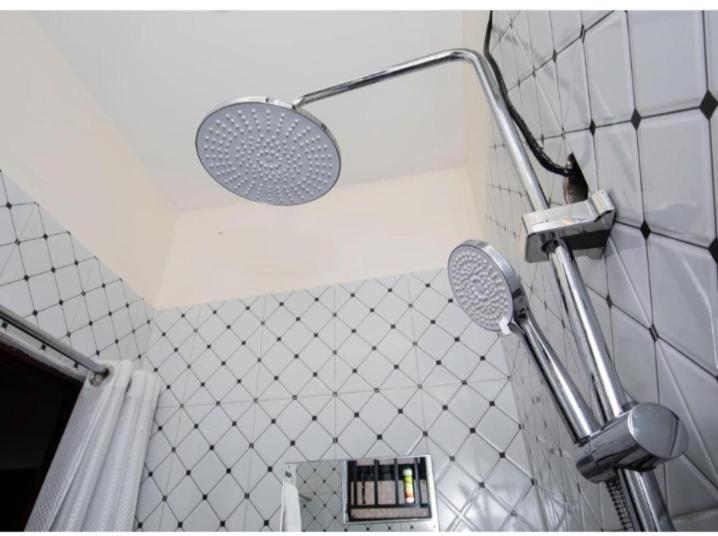 a bathroom with a shower head and a mirror at Javelin Palace Hotel in Kampala