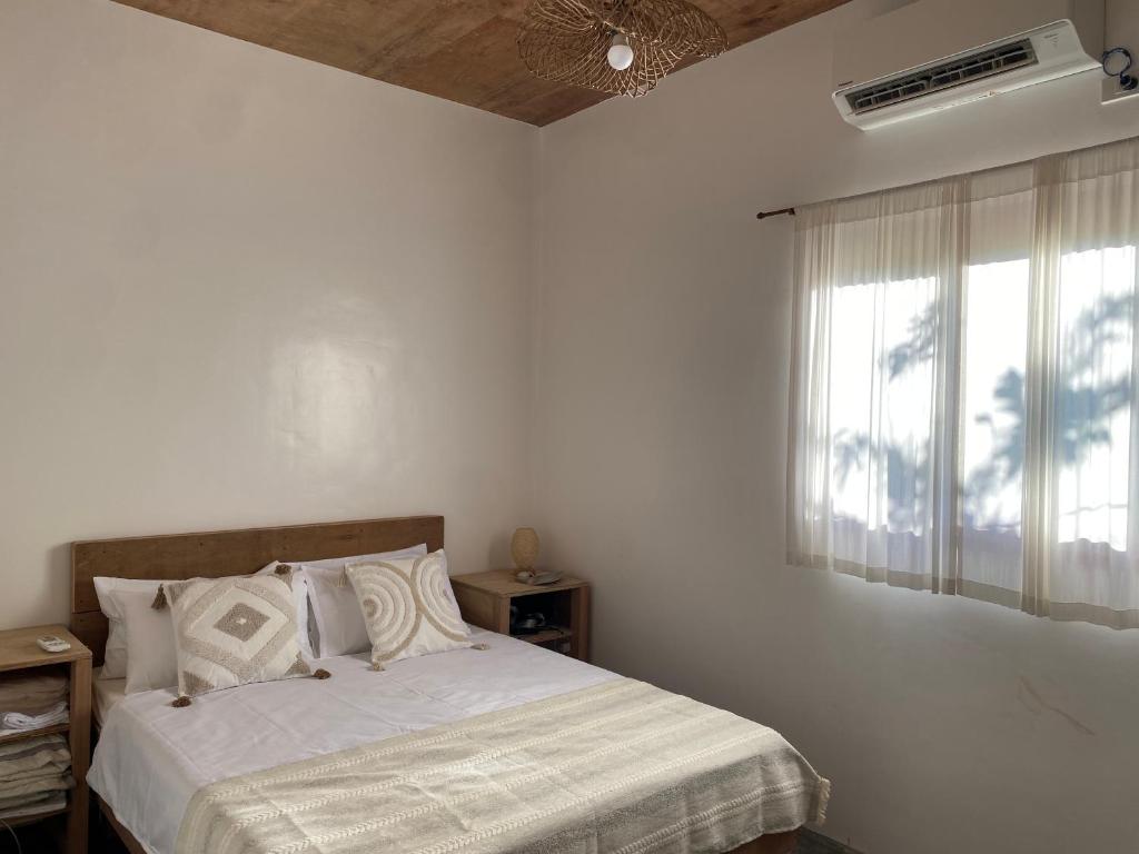 ein weißes Schlafzimmer mit einem Bett und einem Fenster in der Unterkunft Malinka House in Alegria