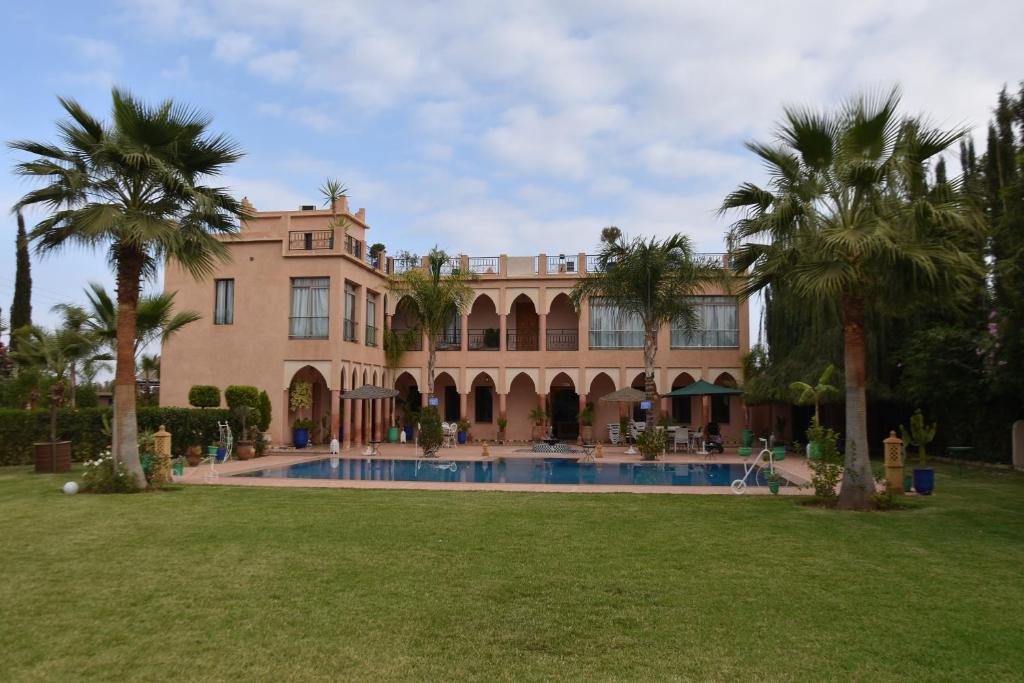 a large house with a swimming pool and palm trees at Les jardins d’ailleurs in Marrakech