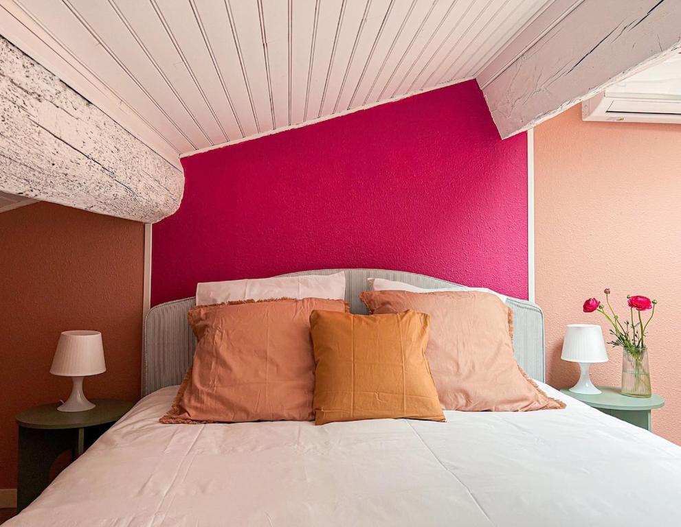 a bedroom with a pink wall and a bed with pillows at Le Mexico Duplex Agréable in Lespignan