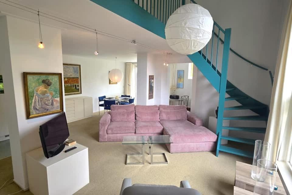 un salon avec un canapé rose et un escalier bleu dans l'établissement Hello Zeeland - Noordstraat 13-01, à Domburg