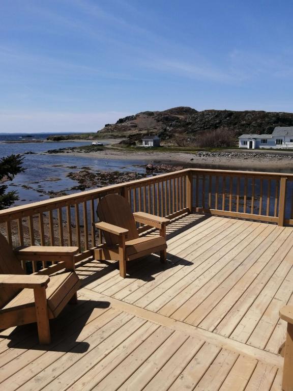 Zwei Holzbänke auf einer Terrasse mit Blick auf das Meer in der Unterkunft Oceanview Cottage in Twillingate