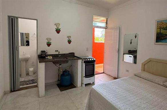 a bathroom with a bed and a sink in a room at Pousada na maranduba suites imperio in Ubatuba