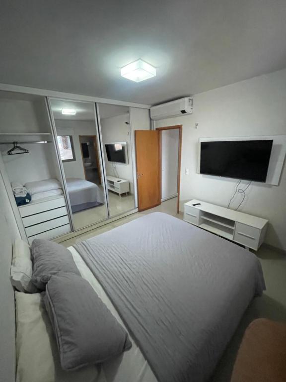 ein Schlafzimmer mit einem großen Bett und einem Fernseher in der Unterkunft Ap 2 quartos em frente ao Campim Dourado Shopping in Palmas