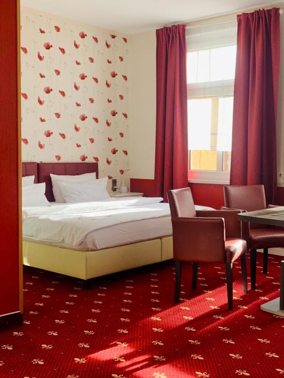 a bedroom with a bed and chairs and a window at Hotel Alt-Connewitz in Leipzig