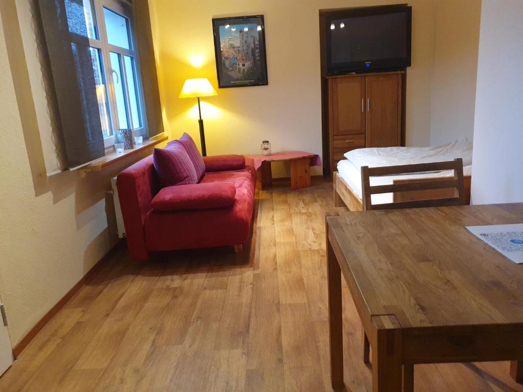 ein Wohnzimmer mit einem roten Stuhl und einem Bett in der Unterkunft Auf dem Bauernhof 