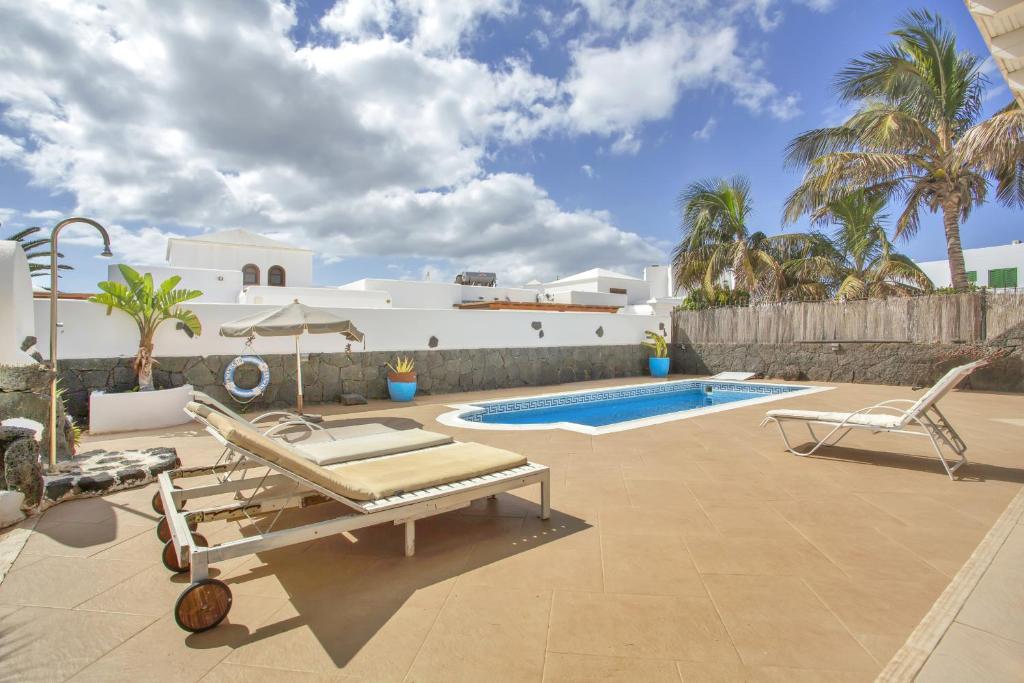 a patio with a pool and chairs and a house at Villa Queen Papagayo Vetusta in Playa Blanca