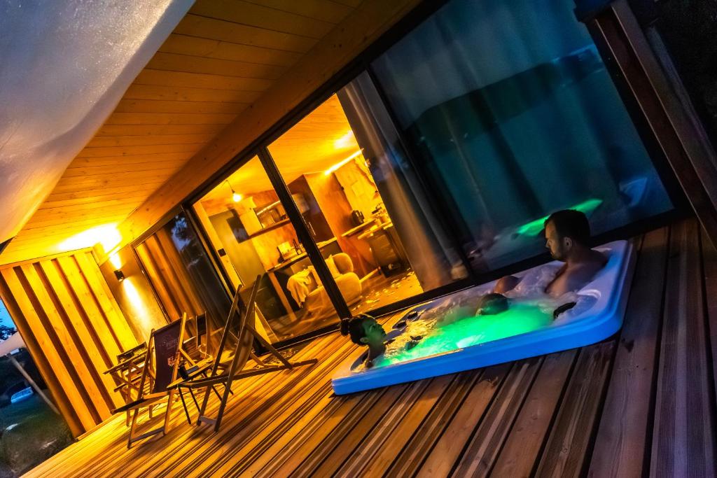 ein Mann in einer Badewanne auf einer Veranda in der Unterkunft Lodges d'Exception avec jacuzzi privé I Montluçon I Auvergne in Prémilhat