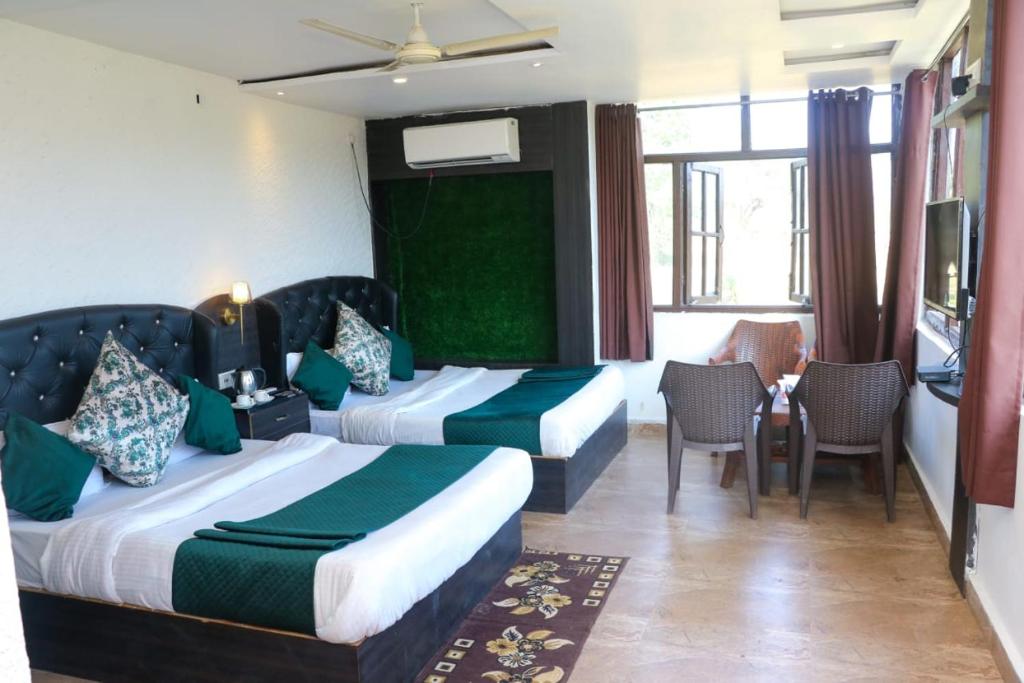 a hotel room with two beds and a table and chairs at Khalsa Lake View Resort in Jāmb
