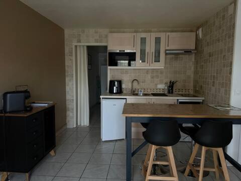 une cuisine avec des armoires blanches et des tabourets de bar dans l'établissement Cabourg Plage - Wifi & Jardin - Mer à 200m, à Cabourg