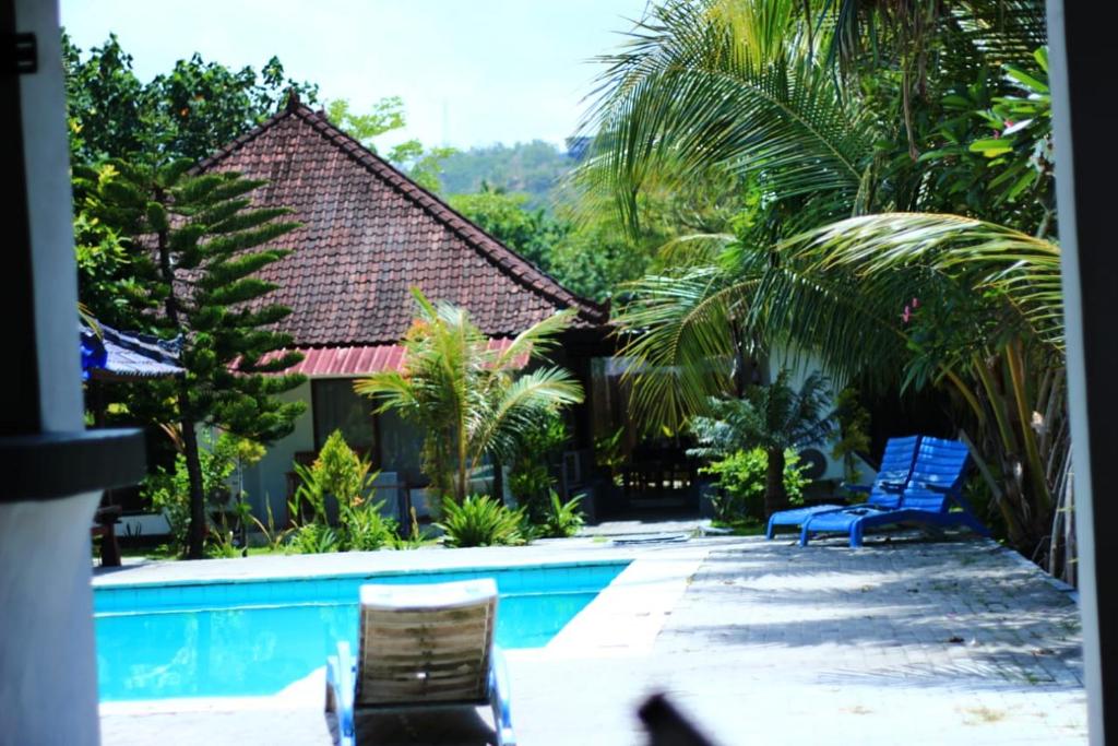 a swimming pool with two chairs and a house at Malaka ocean homestay in Kuta Lombok