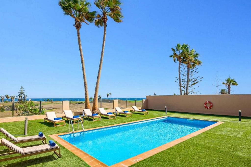 a swimming pool with lounge chairs and palm trees at Villa Humaik by Villa Plus in Antigua