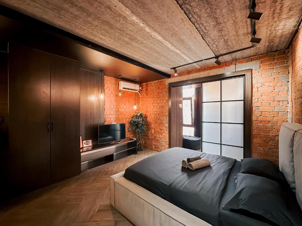 a bedroom with a large bed and a brick wall at Люкс в стиле LOFT in Pavlodar
