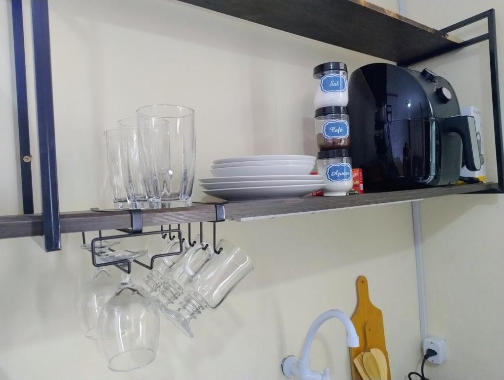 ein Küchenregal mit Tellern und Gläsern darauf in der Unterkunft Loft em rua de comércio em condomínio in Curitiba