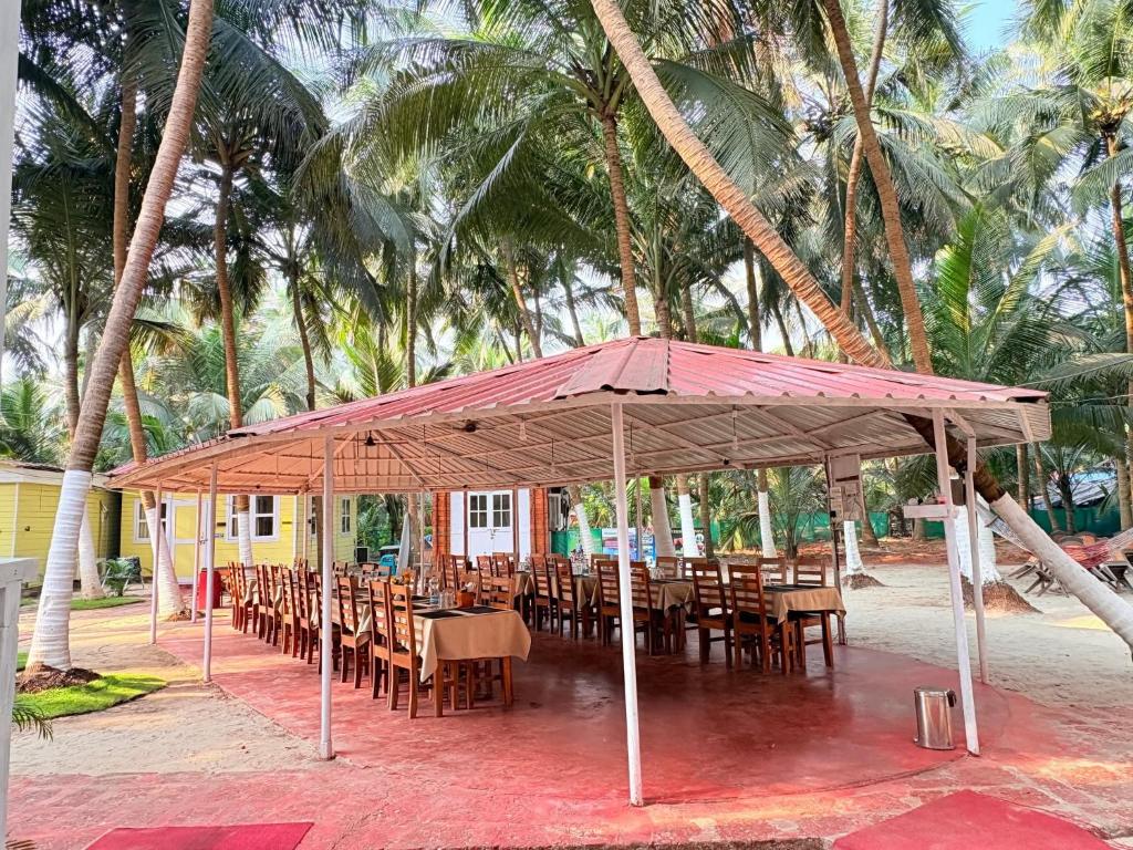 un restaurante con mesas y sillas bajo una tienda en Samant Beach Resort, en Malvan