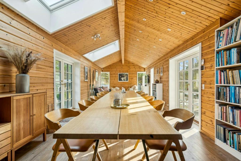 een lange tafel in een bibliotheek met stoelen en boekenkasten bij Timber House On Dune Plot Near Hulsig in Hulsig