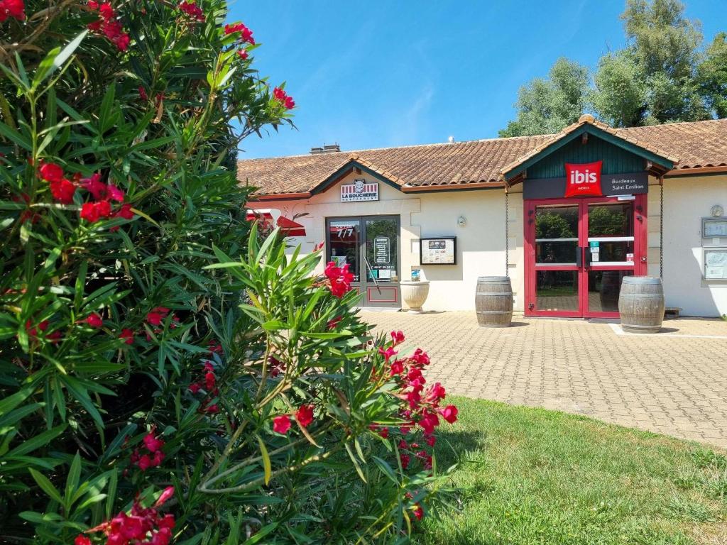 un bâtiment avec un bush et des fleurs rouges devant dans l'établissement ibis Bordeaux Saint Emilion, à Saint-Émilion